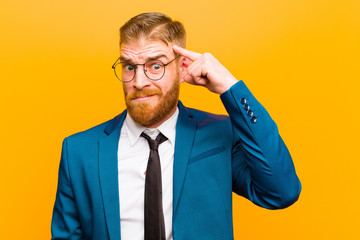 young red head businessman with a serious and concentrated look, brainstorming and thinking about a...