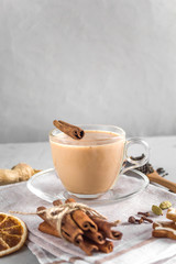 Traditional Indian masala Chai tea with spices on grey concrete background. Hot drink of black tea, milk and spices. Side view, copy space, close-up