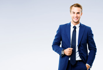 Portrait picture of happy smiling young businessman, over grey background. Business success concept.