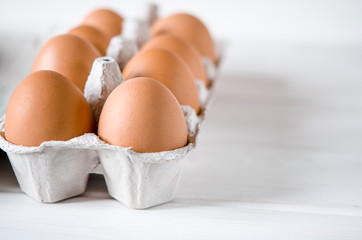 Large brown chicken eggs lie in an eco-friendly cardboard egg tray
