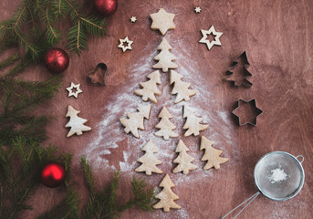 Christmas tree made from gingerbread cookies, sugar powder, fir tree and festive decoron on a brown wooden table. Holiday and cooking concept. Christmas and new year postcard. Top view