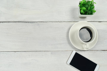 Coffee and smartphone on white wooden table background. office supplies concept.
