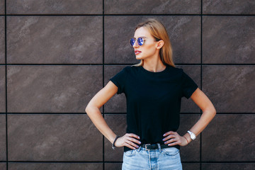Girl wearing t-shirt, glasses and leather jacket posing against street , urban clothing style....