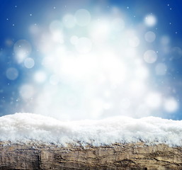 Winter background with snow and blur abstract lights. Empty wooden plank. Copyspace for text.