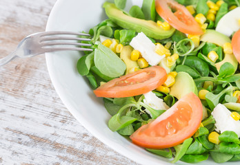 .Organic salad leaves: arugula, watercress, lettuce, corn and tomato in a bowl. Close up.
