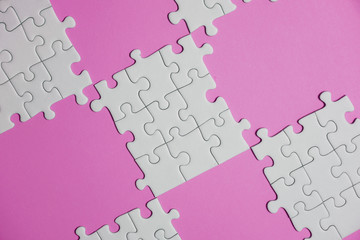 Fragment of a folded white jigsaw puzzle and a pile of uncombed puzzle elements against the...