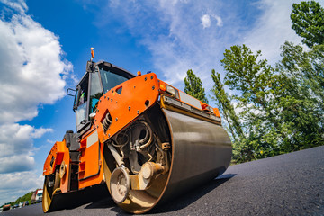 Road repair, compactor lays asphalt. Heavy special machines. Asphalt paver in operation. Side view....