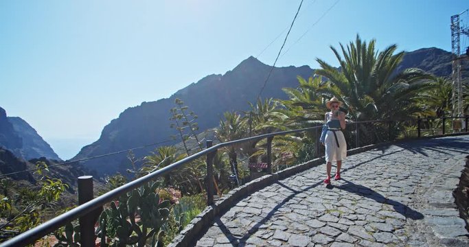 Masca, Santa Cruz de Tenerife. Glorious scenery of Masca valley spanish village on sunny day. Happy woman tourist walking on viewpoint admiring summer vacation.