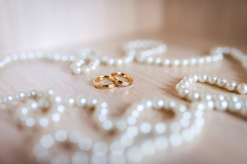 A pair of gold wedding rings in the white pearl background. Closeup.