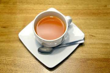 White cup with sea-buckthorn tea stands on a saucer