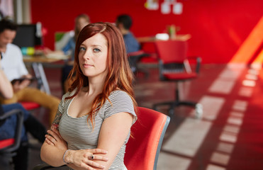 Confident female designer working in red creative office space