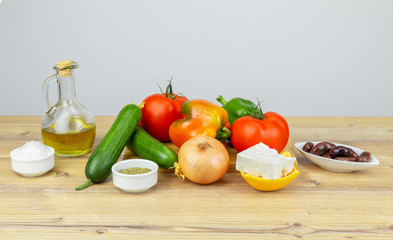 Ingredients for Greek Salad on wooden background. Vegetables on wooden background. Healthy food, Mediterranean diet. Copy space for text. Salad ingredients, tomatoes, feta, cucumber, onion, olive oil.
