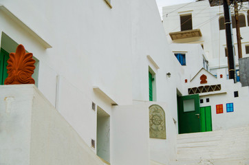 White stairs in romantic backstreet alley lane alleyway street with traditional typical Greek white buildings and colorful blue white buildings and balconies on Sifnos in Greece