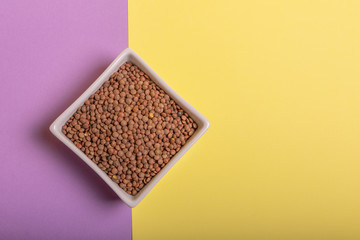 Lentils in a white ceramic bowl, on colored cardboards