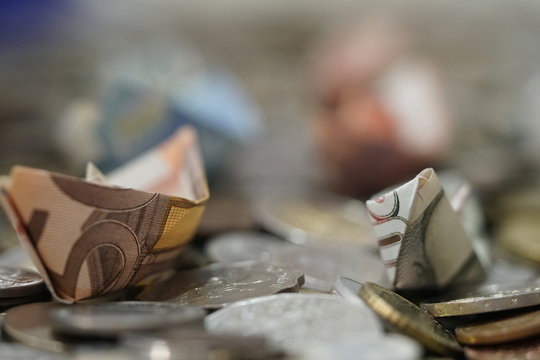 coins bills billetes de curso legal de euros hechos barquitos de papel navegando sobre monedas del mundo