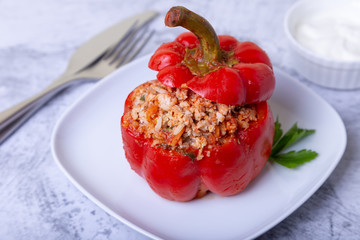 Peppers stuffed with meat, rice and vegetables with tomato sauce and sour cream. A traditional dish. Close-up.