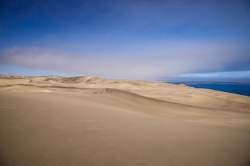 Fototapeta na wymiar Dune de sable jaune dominant l'océan Atlantique en Namibie - Afrique