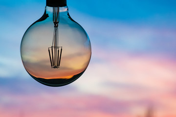 Fototapeta na wymiar Beautiful defocused sunset in a light bulb. Sunset or sunrise background. Electricity concept. Earth hour. Energy consumption and environmental conservation, energy saving