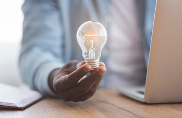 Black businessman holding illuminated light bulb in hand