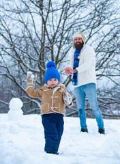 Father and son in snow. Happy father and son - winter portrait. Dad and baby son playing together outdoors.