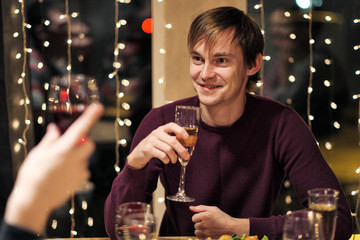 Friends holiday party dinner at home around the table. Celebrate Christmas. People eat, drink champagne, talk and laugh.