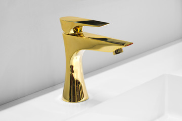 Luxury golden mixer on a white sink in a beautiful gray bathroom