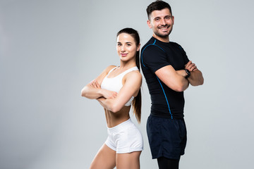 Portrait of a sporty young couple with arms crossed over white background