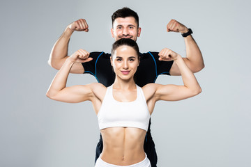 Beautiful athletic couple show biceps on gray background