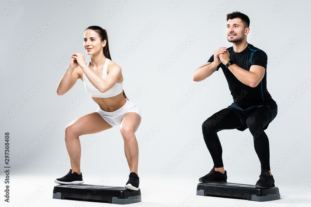 Wall mural Athletic couple doing exercises over steps in aerobic class isolated on white background. Sport and health concept.