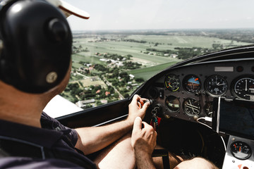View from pilot's cabin. Control panel. Close up of a pilot flying airplane over the fields and village. Many buttons, navigation devices on dashboar © Vadym