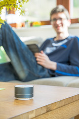 Fototapeta premium Smart ai speaker with child playing on tablet in the backround. Smart home concept