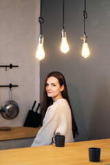 Portrait of a young beautiful woman in a warm sweater and with a cup of hot drink at home on the...