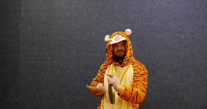 funny teacher wearing cute Kigurumi tiger pajama costume playing the gong, can be used for education purpose