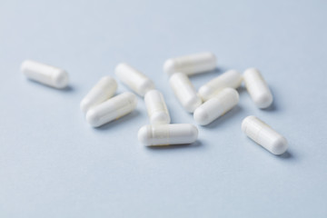 Arginine capsules. Bright paper background. Close up. 