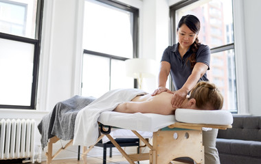 Chinese woman massage therapist giving a treatment to an attract