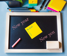 New year new you concept, Wood chalk board and colorful paper with pen, pencil and clips in light blue background