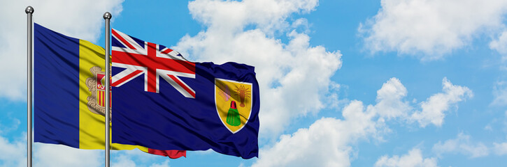 Andorra and Turks And Caicos Islands flag waving in the wind against white cloudy blue sky together. Diplomacy concept, international relations.