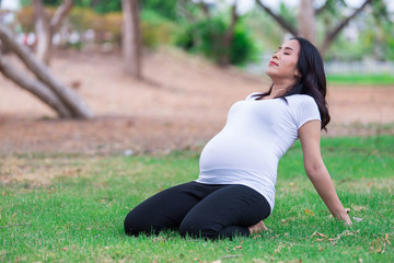 Portrait of asian Beautiful pregnant woman at the park,Thailand people,Happy woman concept,Her play yoga on the lawn