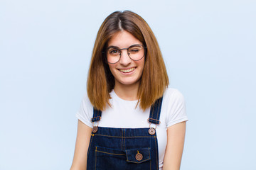 young pretty woman looking happy and friendly, smiling and winking an eye at you with a positive...