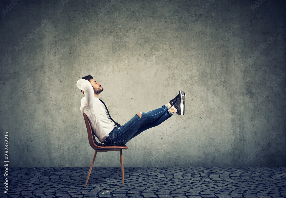 Wall mural Happy casual business man sitting on chair with feet up relaxing