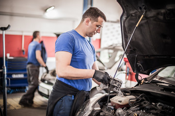 Fototapeta na wymiar Two car mechanic repairers service technician repairs auto engine