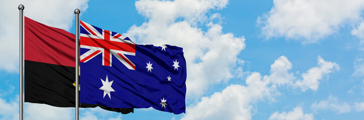 Angola and Australia flag waving in the wind against white cloudy blue sky together. Diplomacy concept, international relations.