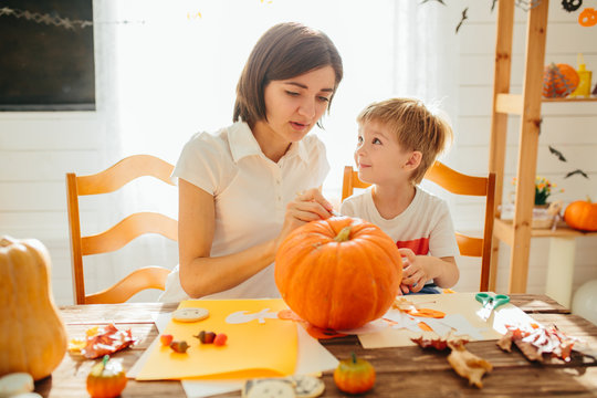 Happy halloween. Young beautiful mother and her son carving pumpkin. Happy family preparing for Halloween. Happy Halloween concept