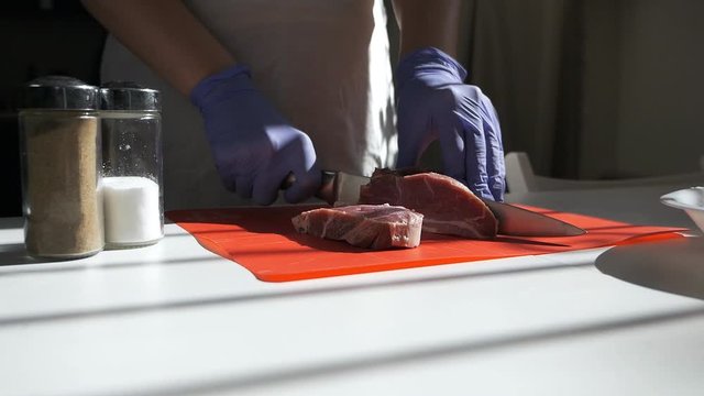 Cook cutting up an meat with a knife. Hands cutting fresh meat Close-Up. Cutting fresh meat into steaks.