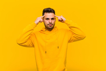 young hispanic man with a serious and concentrated look, brainstorming and thinking about a...