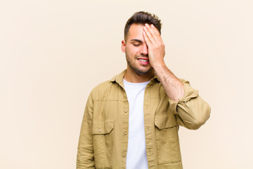 young hispanic man laughing and slapping forehead like saying d‚Äôoh! I forgot or that was a...