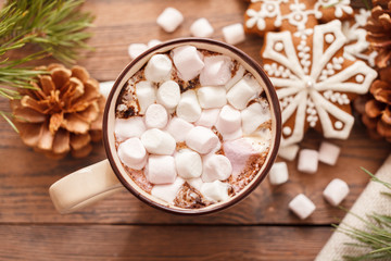 A beige Cup of traditional Christmas hot chocolate or cocoa with marshmallow. Christmas gingerbread on wooden background