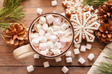 Obraz na płótnie Canvas A beige Cup of traditional Christmas hot chocolate or cocoa with marshmallow. Christmas gingerbread on wooden background