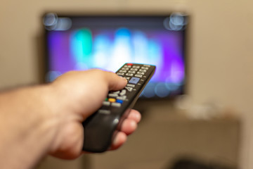 A person with a TV remote controls the remote control to switch channels to watch TV shows.