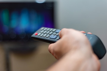 A person with a TV remote controls the remote control to switch channels to watch TV shows.